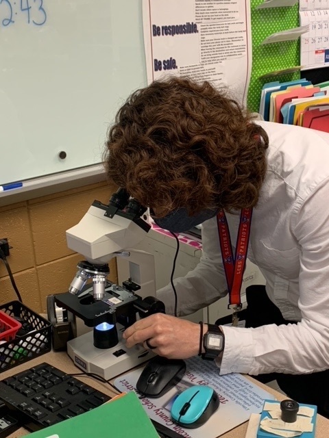 teacher looking at microscope 