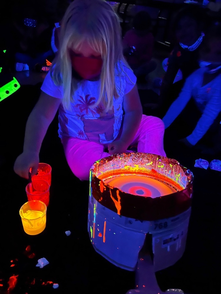 Student participating in glow party.  Paint that glows in a bucket. 